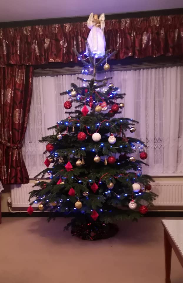 Christmas tree decorated with red and gold ornaments, blue lights, and an angel on top.