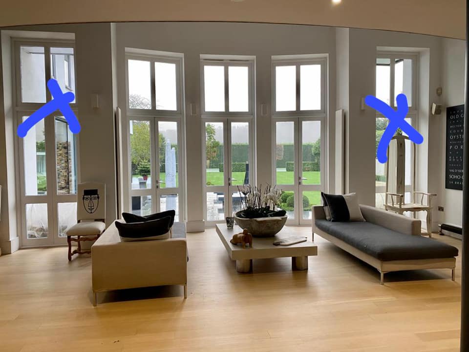 Living room with large windows overlooking a yard, furnished with a couch, coffee table, and chairs.