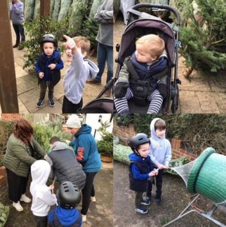 Children with helmets and adults buying Christmas trees, outdoor setting.