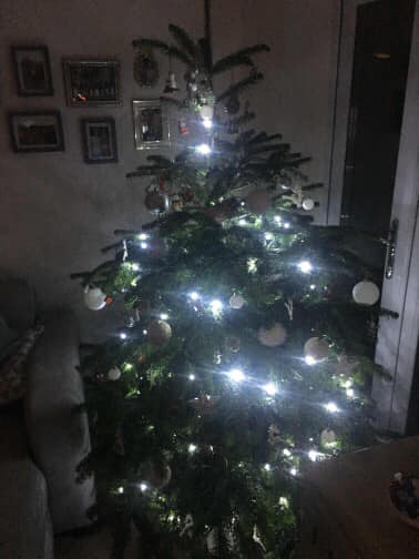 Christmas tree with white lights and ornaments, indoors.