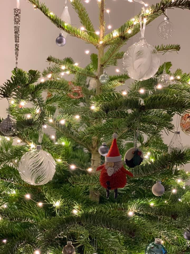 Christmas tree decorated with ornaments and fairy lights. A small Santa figure is centered.
