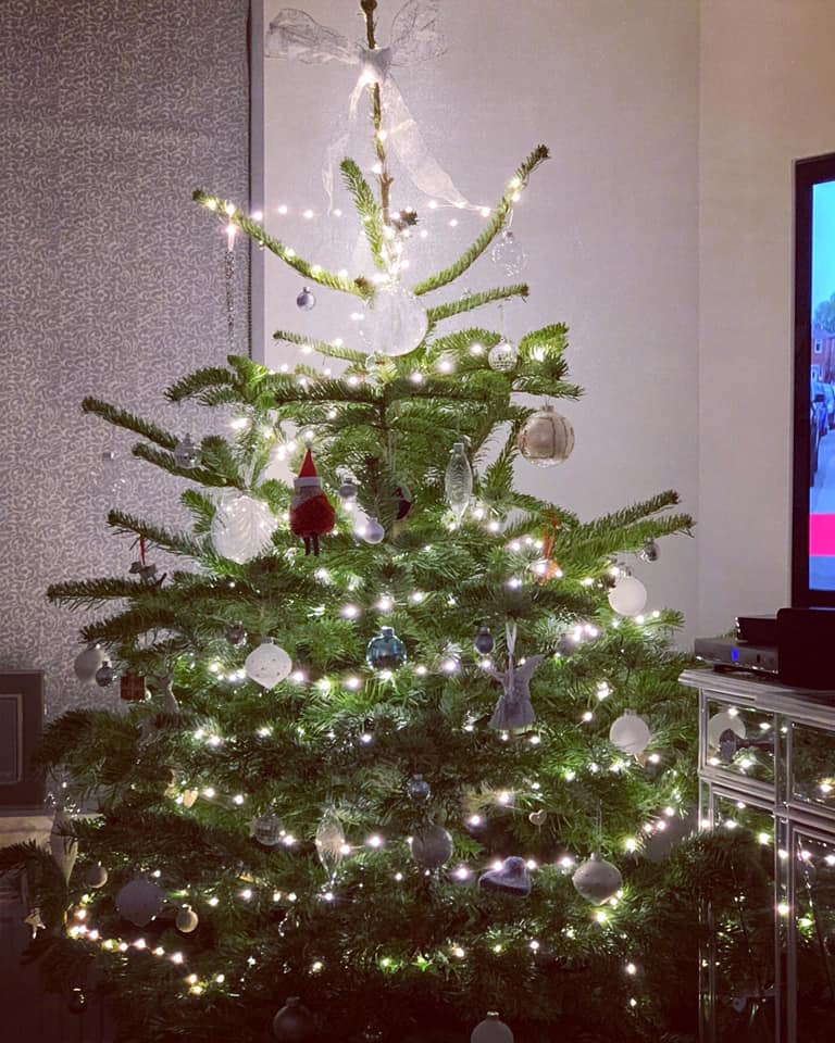 Christmas tree decorated with white lights and ornaments indoors.