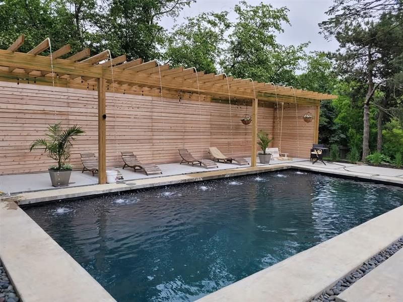A large swimming pool with a wooden pergola over it