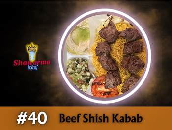 Beef shish kabab on yellow rice, with salad, tomato, and a white roll, in a lit circular frame.