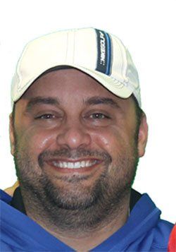 A man with a beard wearing a white hat that says atomic on it