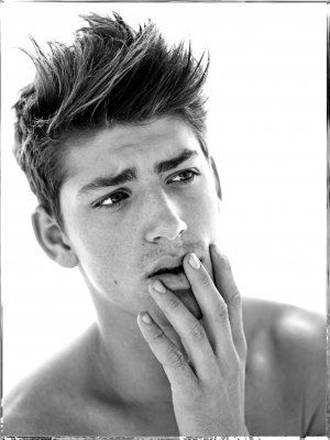 A black and white photo of a young man with his hand on his face