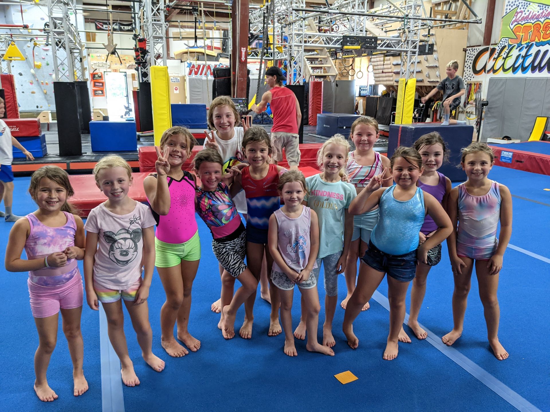 Group of barefoot girls smiling and posing in a gymnastics gym.