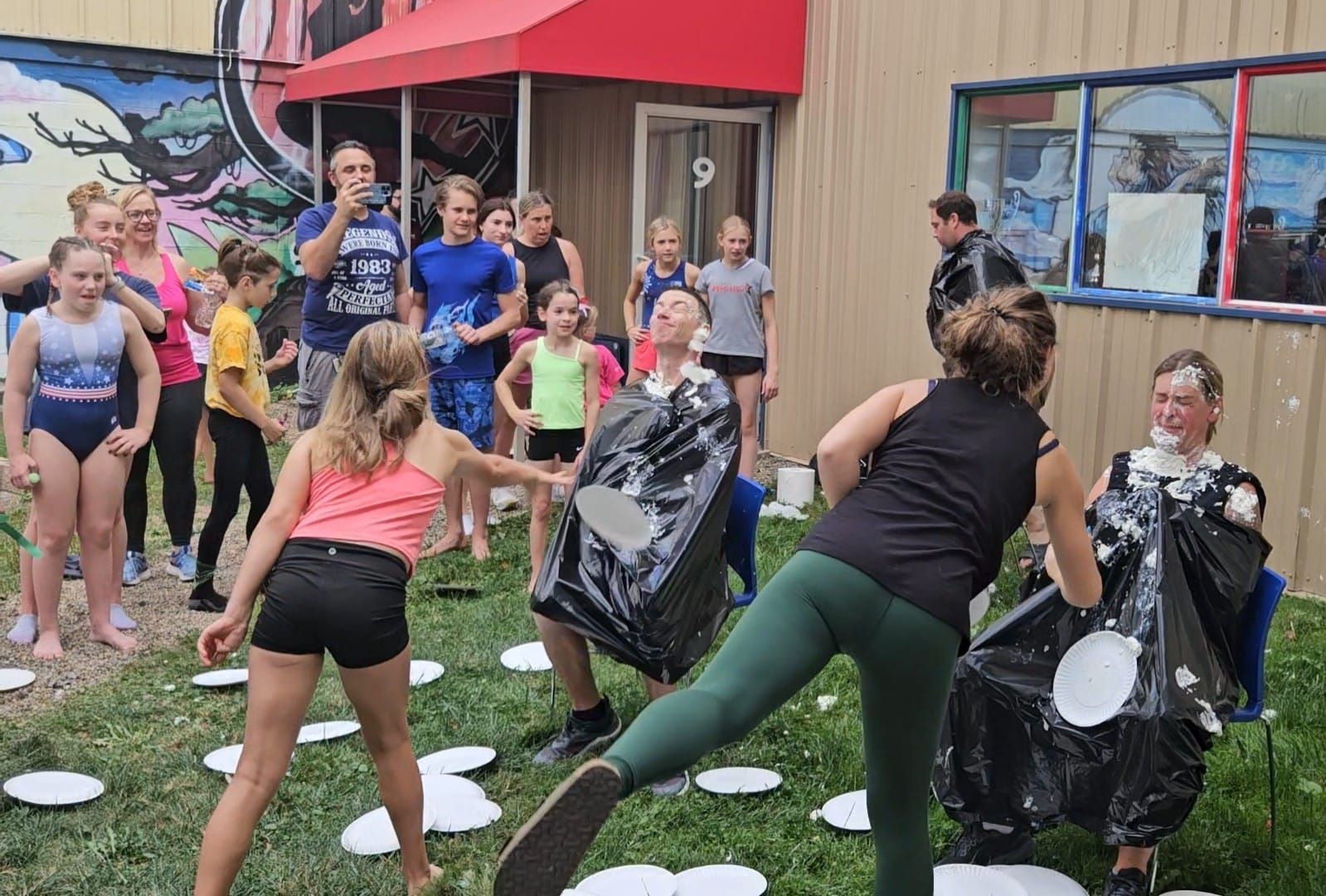 People covered in pie during an outdoor event, surrounded by other kids.