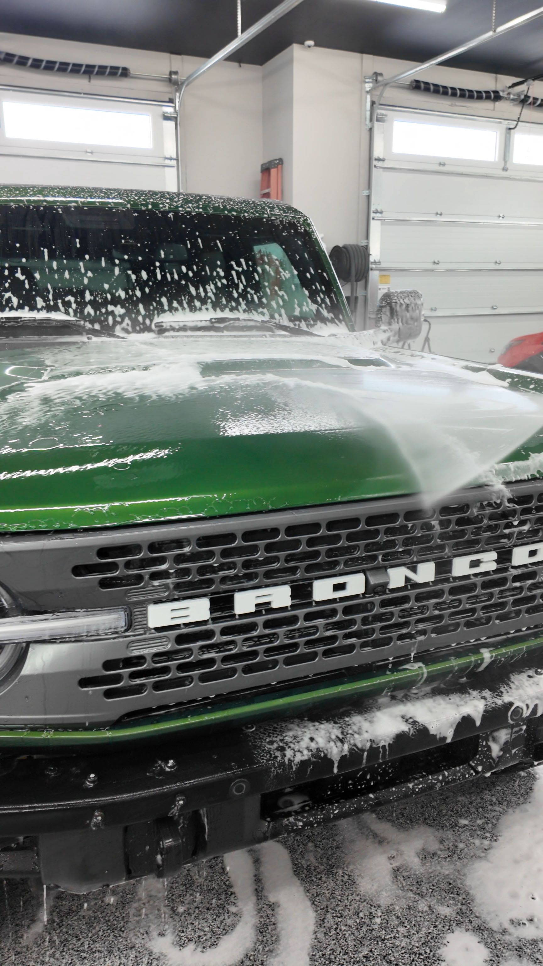 A car is being washed with foam in a garage.