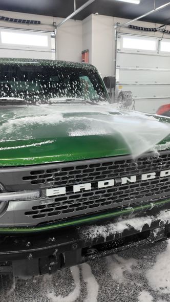 A car is being washed with foam in a garage.