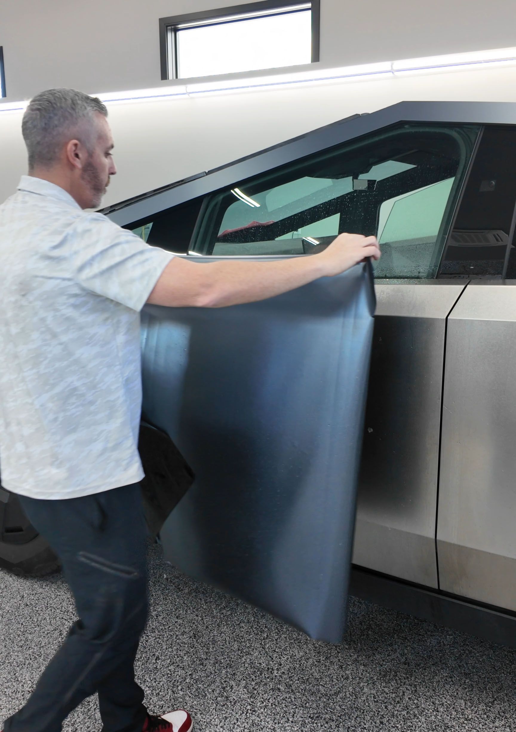 A person wearing black gloves is polishing a black car