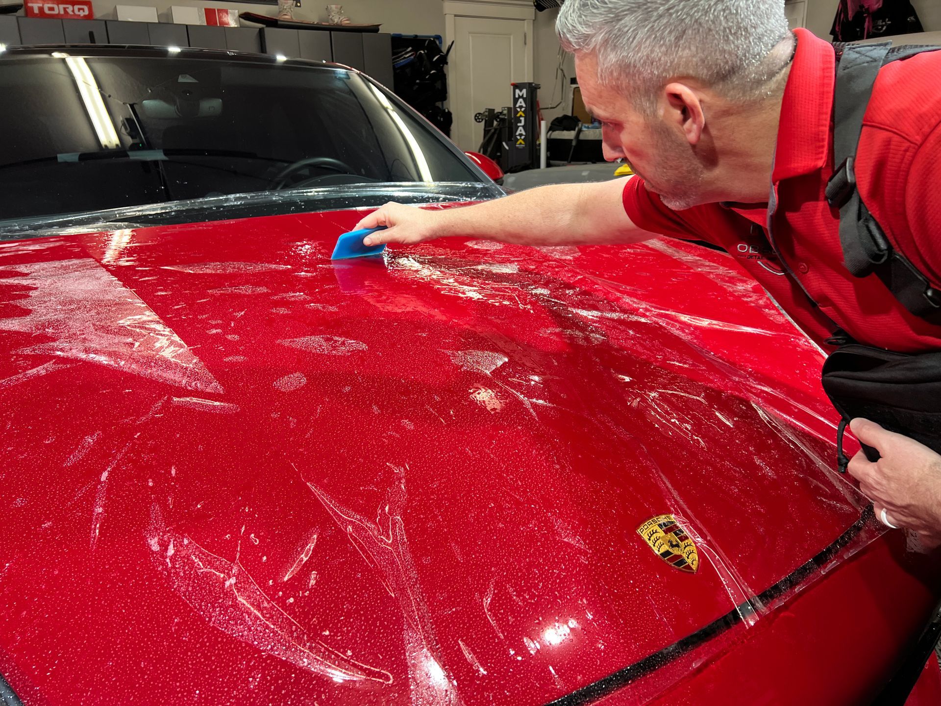 man installing a paint protection film for a red car