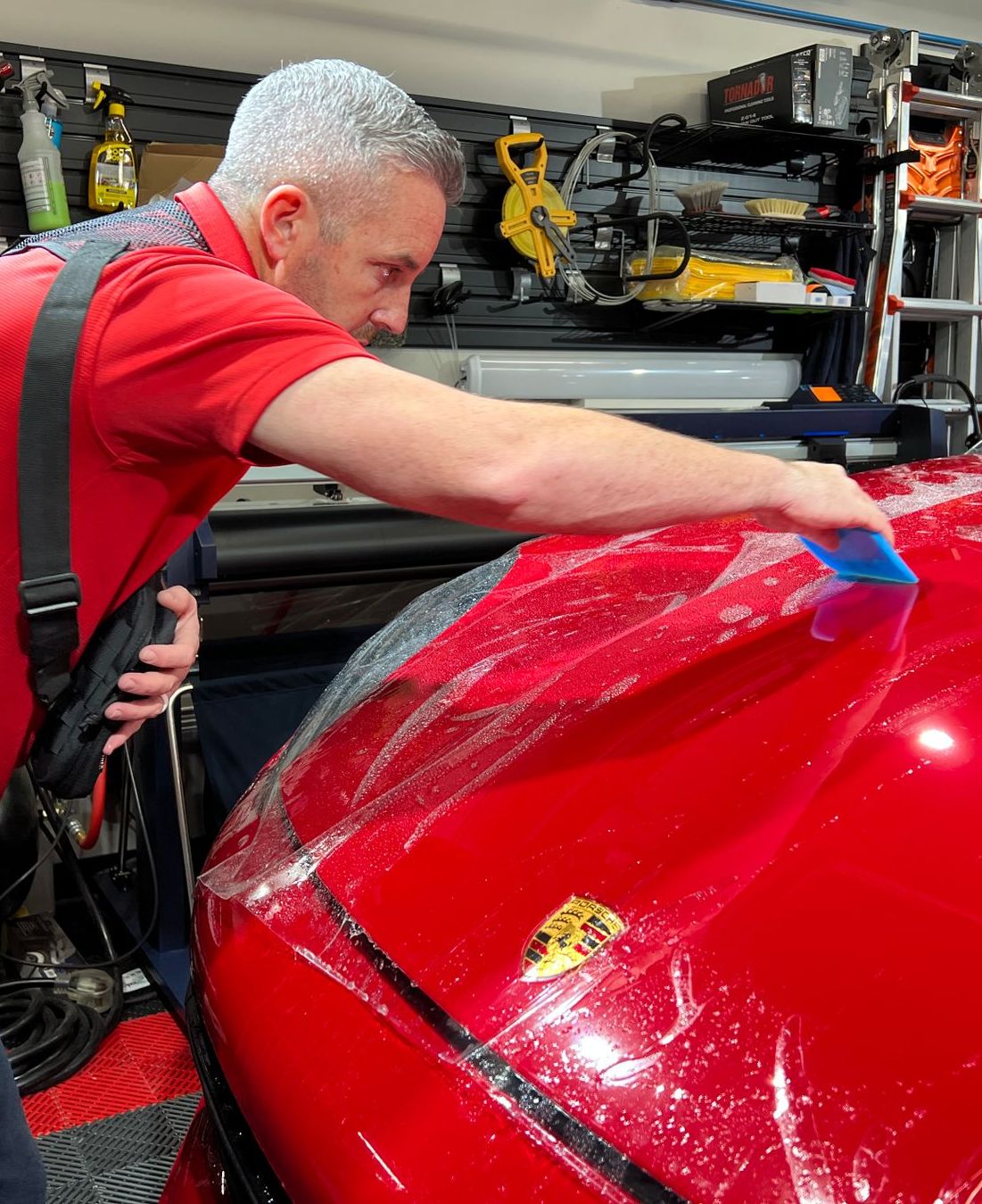 A person is cleaning a car with a blue sponge.