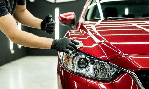 A man is polishing a red car in a garage.