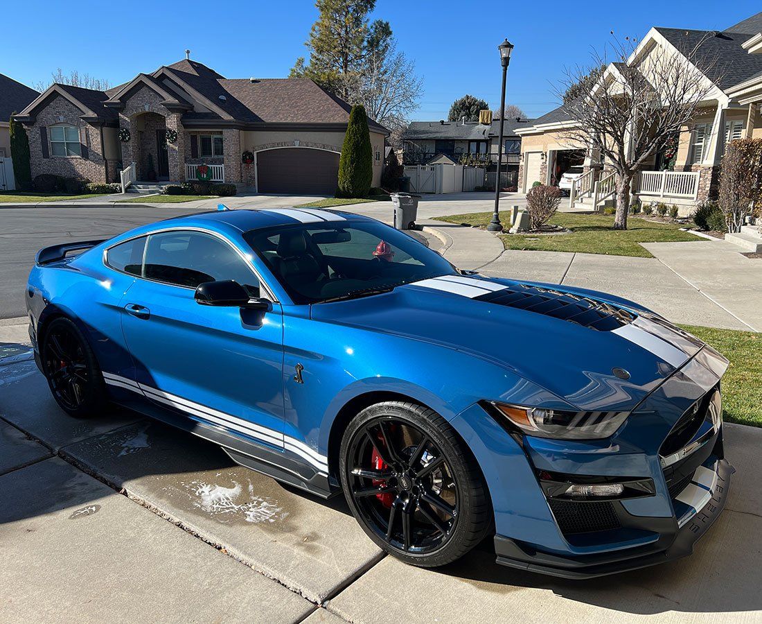 sleek blue sports car parked in a residential driveway