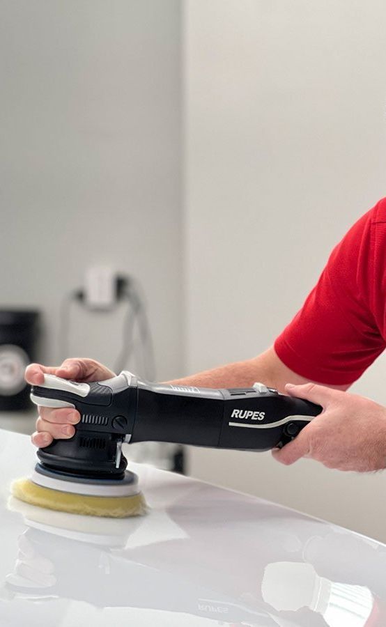 A man is cleaning the wheel of a black car with a sponge.
