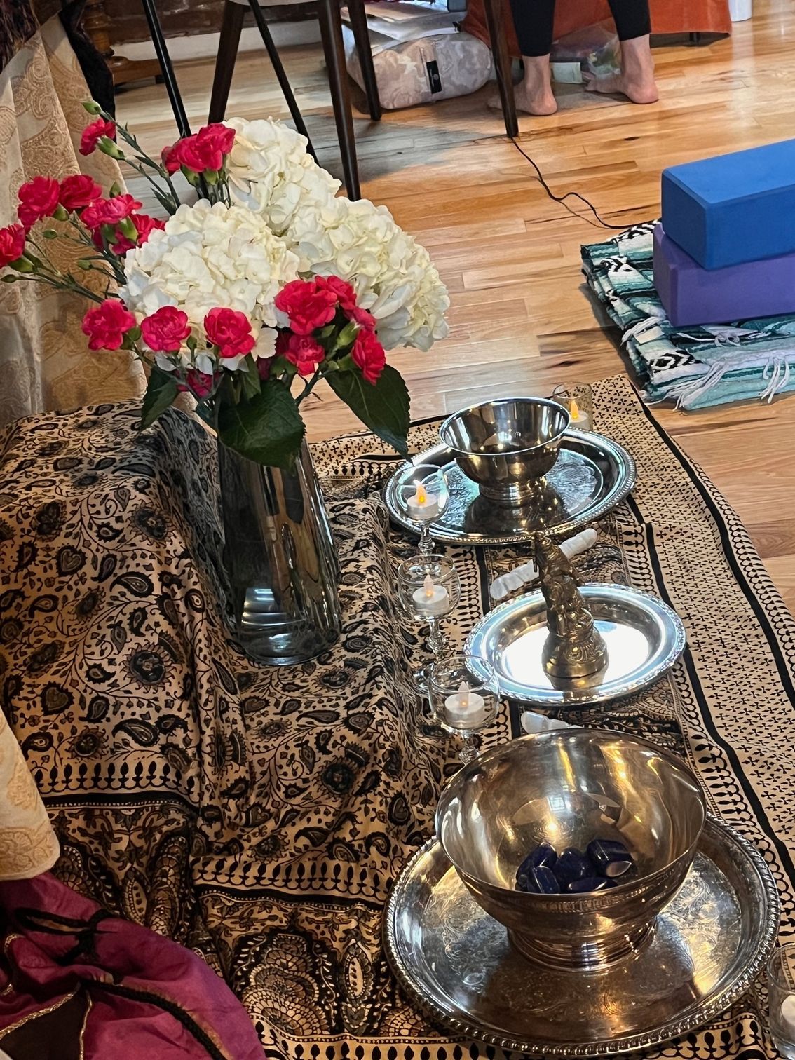 Two women leaning on a table, looking pensive. One has dark hair, the other has long, wavy hair. Papers in front of them.