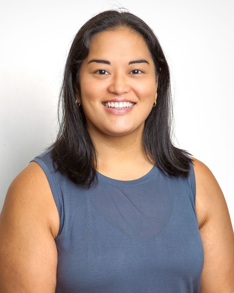 Woman with dark hair smiling widely, wearing a striped top, outdoors.
