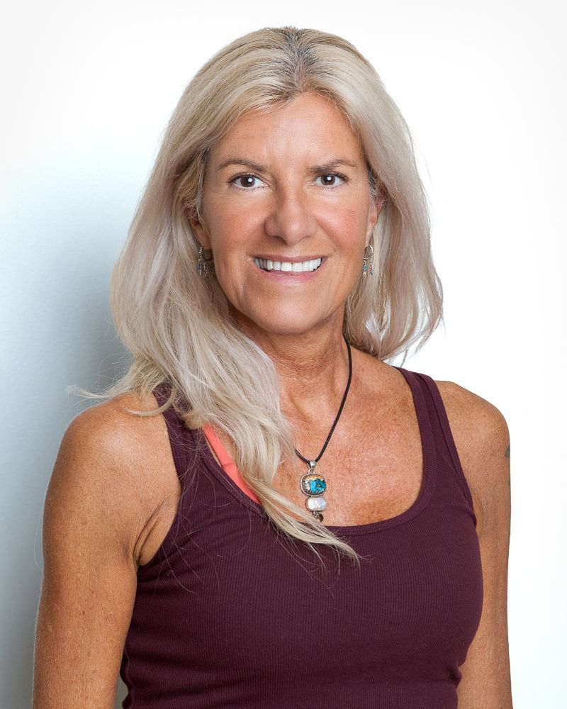 Woman with long dark hair smiles, possibly outdoors.