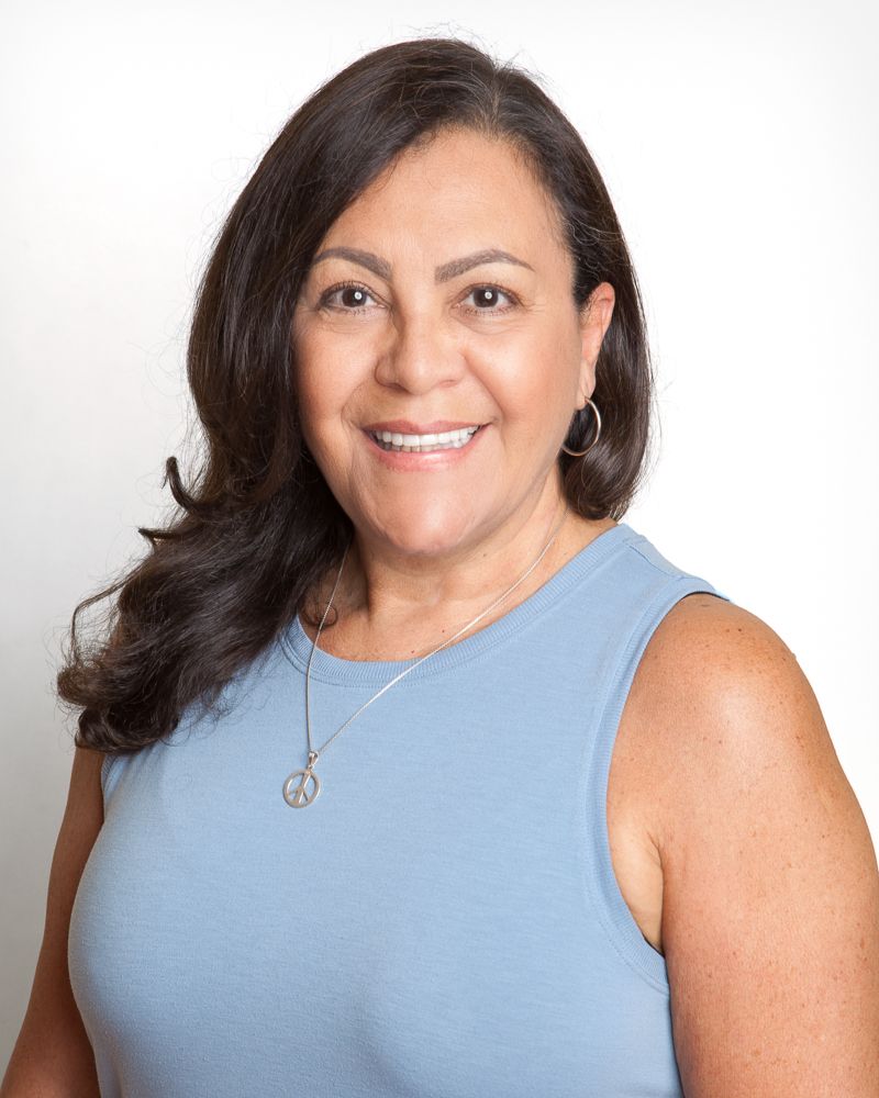 Smiling woman with dark hair, wearing a coral-colored button-down shirt.