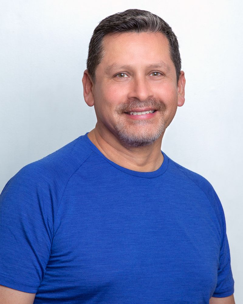 Smiling man in a pink shirt; outdoors.