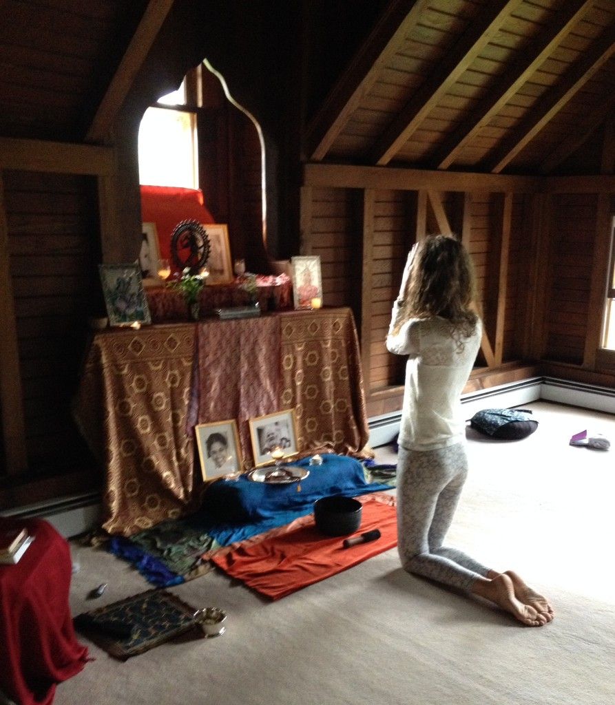 Woman kneeling in prayer before an altar in a wooden room.