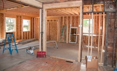 A room in a house under construction with a ladder and a shovel.