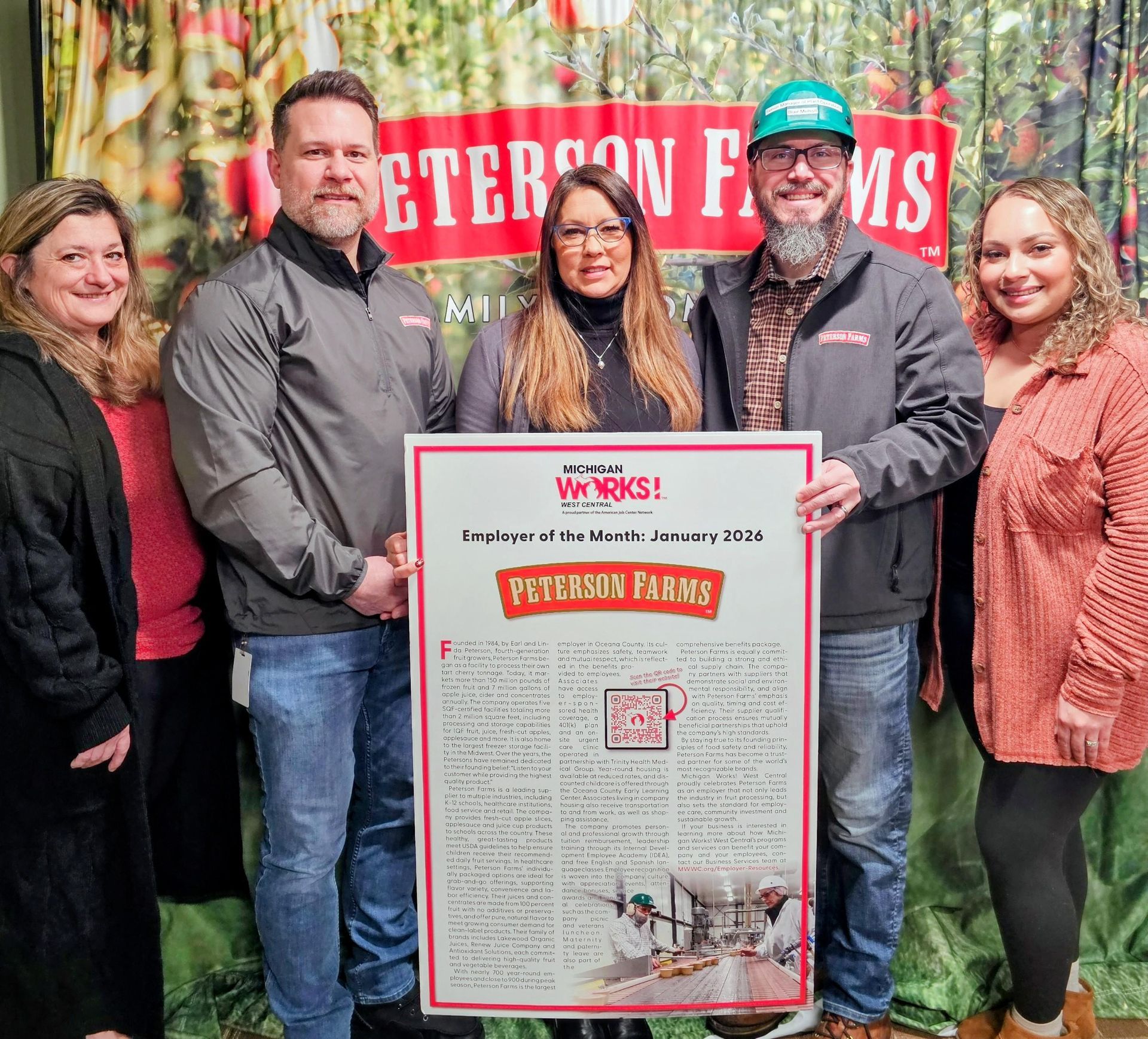 People holding a framed document, standing in front of a backdrop with 