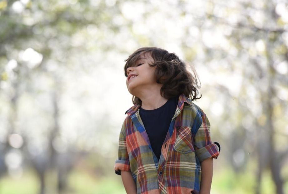 A man is writing on a clipboard while sitting next to two children.