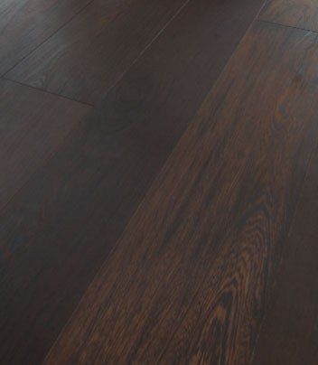 Eine Nahaufnahme eines dunklen Holzbodens in einem Raum.