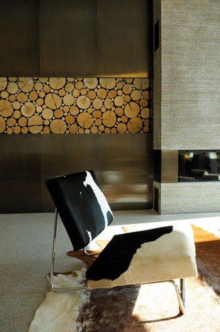 Ein Wohnzimmer mit einem Stuhl und einem Kamin mit Holzscheiten an der Wand