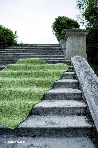 Auf einer Treppe liegt ein grüner Teppich.