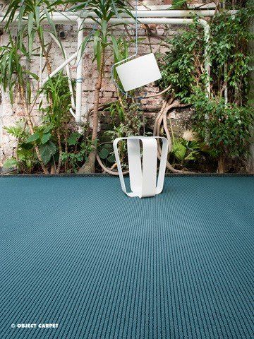 Auf einem blauen Teppich stehen ein Stuhl und eine Lampe.