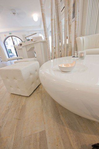 Ein weißer Couchtisch mit einer Schale voller Kerzen darauf in einem Wohnzimmer.