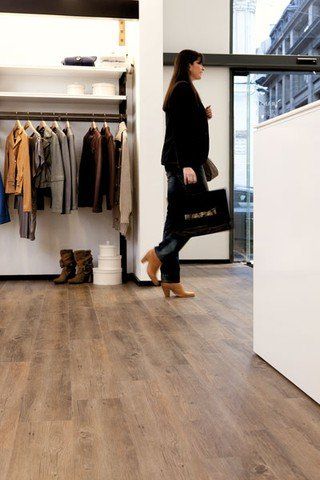 Eine Frau geht mit einer Tasche in der Hand durch ein Bekleidungsgeschäft.