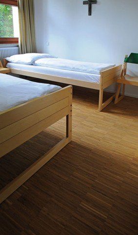 Ein Schlafzimmer mit zwei Betten und einem Kreuz an der Wand.