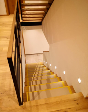 Eine Holztreppe mit gelben Stufen und einem schwarzen Geländer