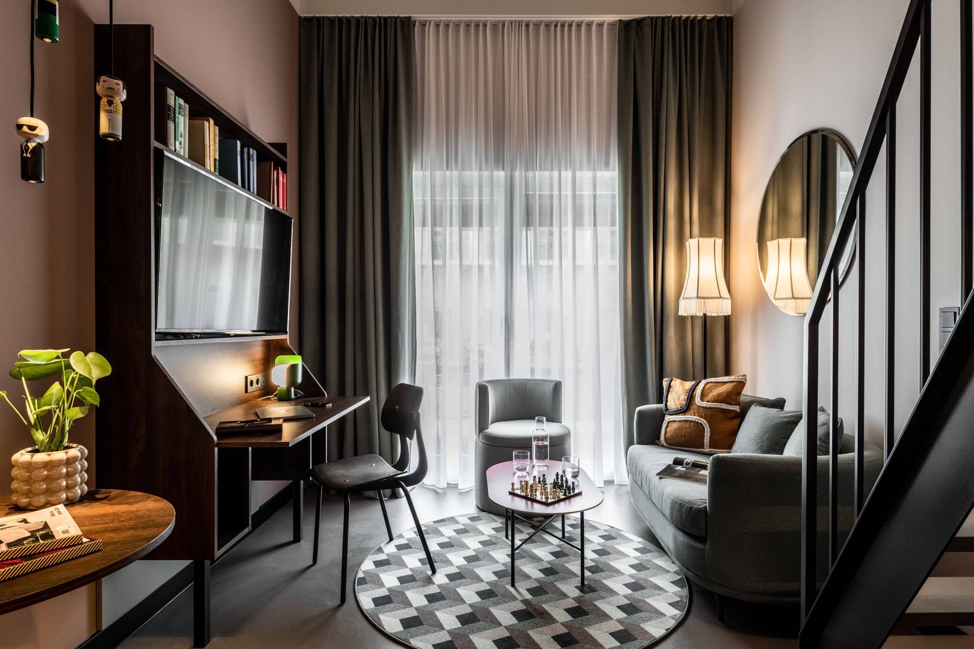 Ein Wohnzimmer mit Couch, Schreibtisch, Stühlen und Treppe.