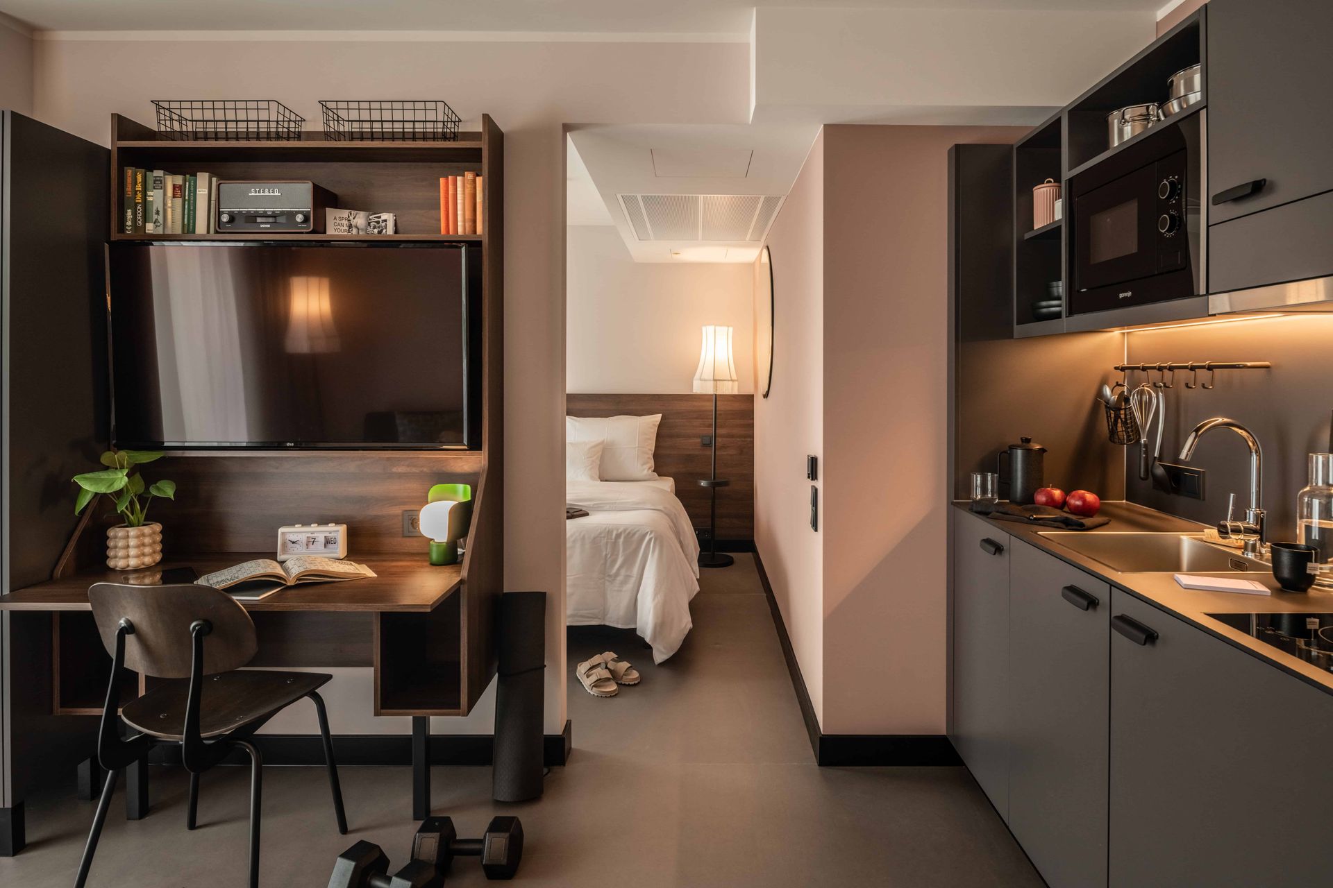 Ein Hotelzimmer mit Schreibtisch, Stuhl, Fernseher und Küche.