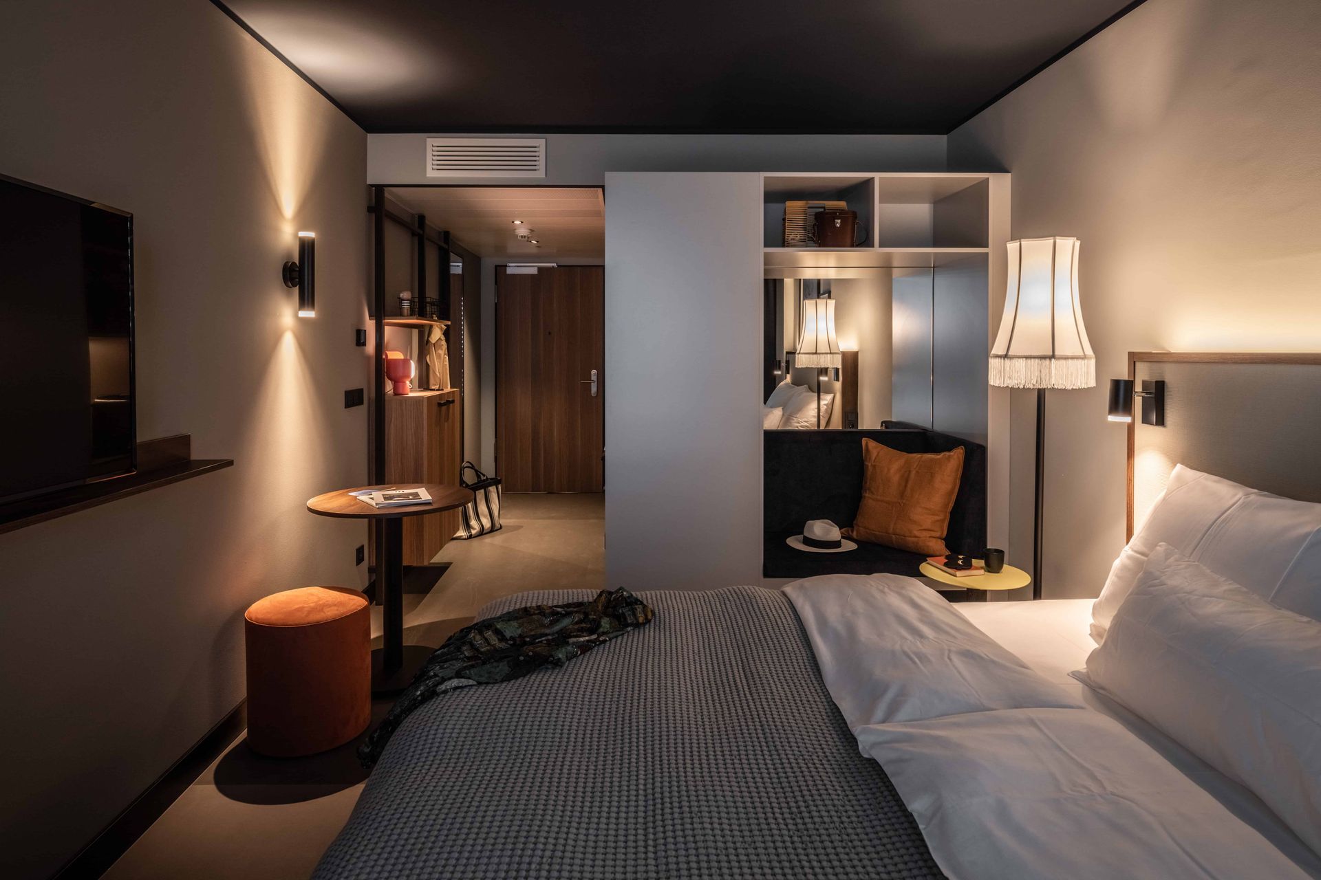 Ein Hotelzimmer mit Bett, Couch, Tisch und Lampe.