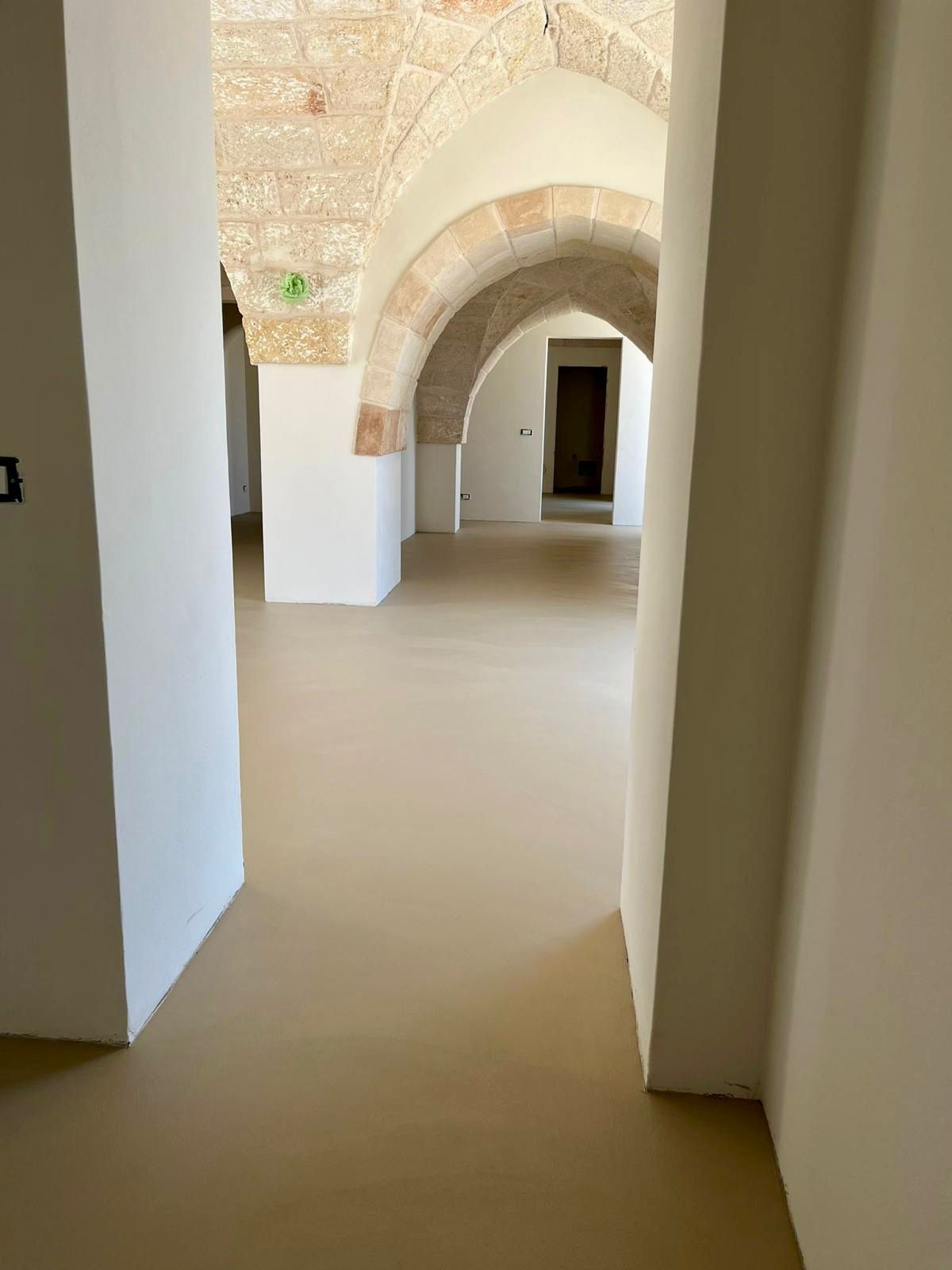 Un corridoio con archi e pavimento marrone in un edificio.