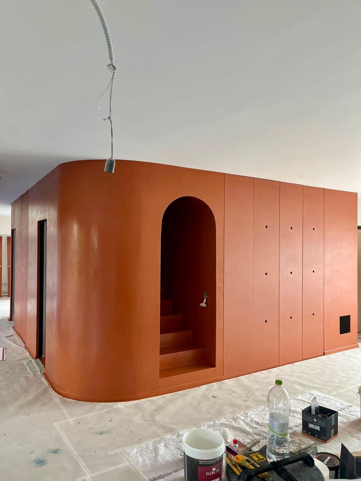 Una stanza con pareti arancioni e una bottiglia d'acqua sul pavimento.