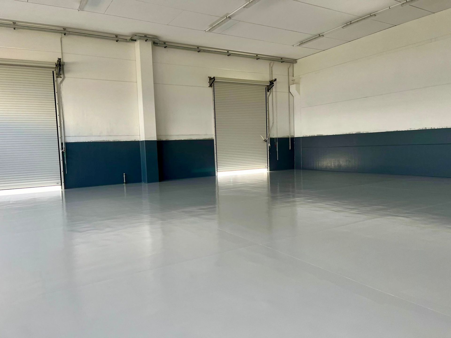 Un grande magazzino vuoto con pavimento bianco e pareti blu.