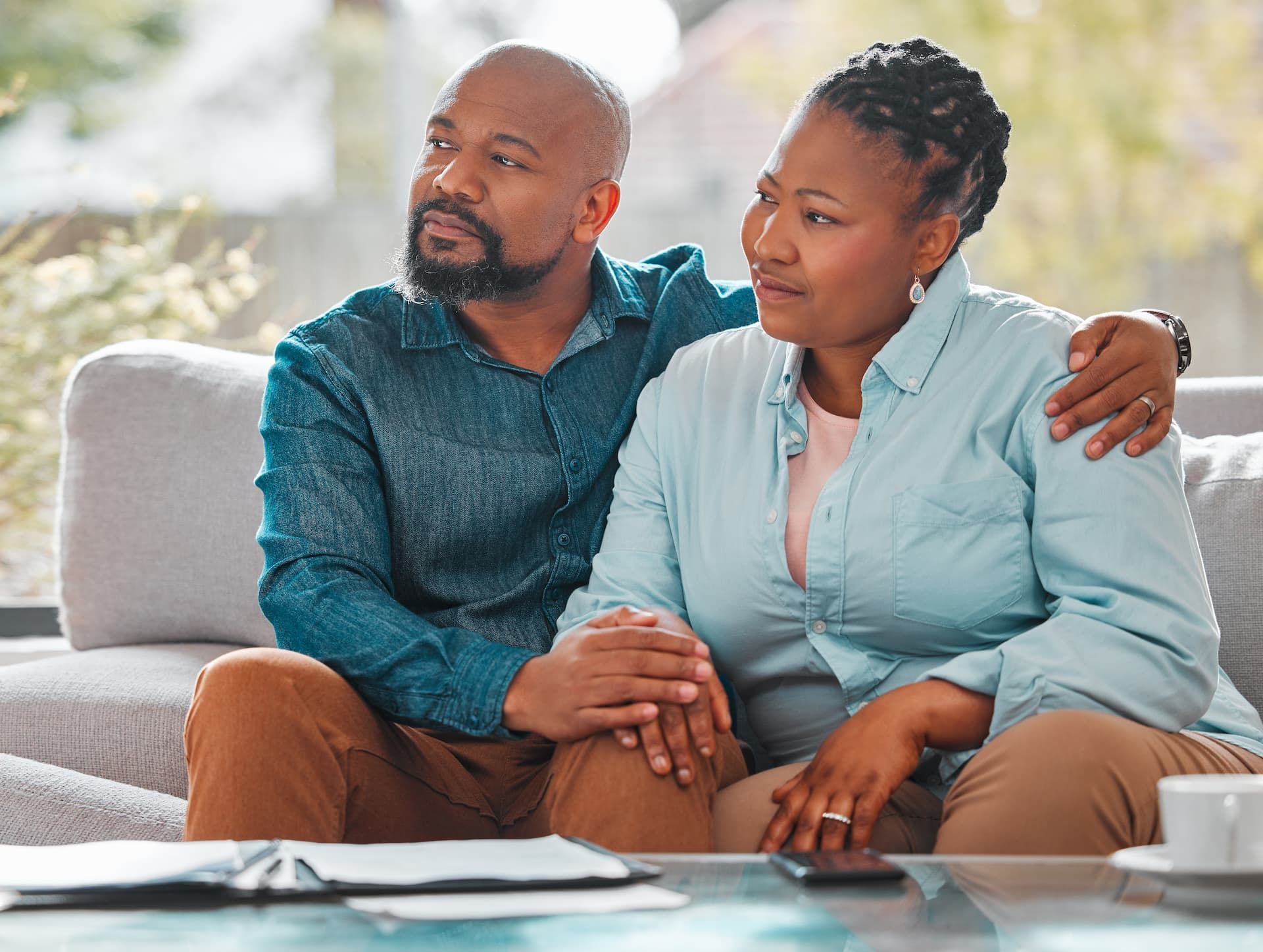 An elderly couple is sitting at a table with a laptop and a notebook.