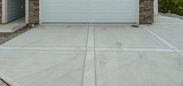 A concrete driveway with a garage door in the background.