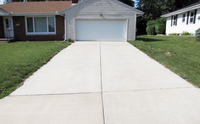 A concrete driveway leading to a house with a garage.