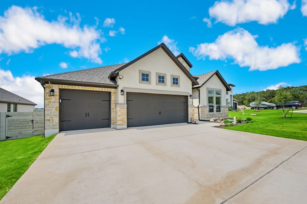 A house with two garages and a driveway in front of it.