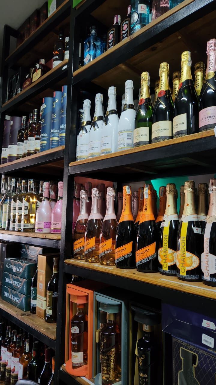 Estantes de botellas de licor en una tienda. Destacan las botellas de champán con etiquetas doradas y negras.