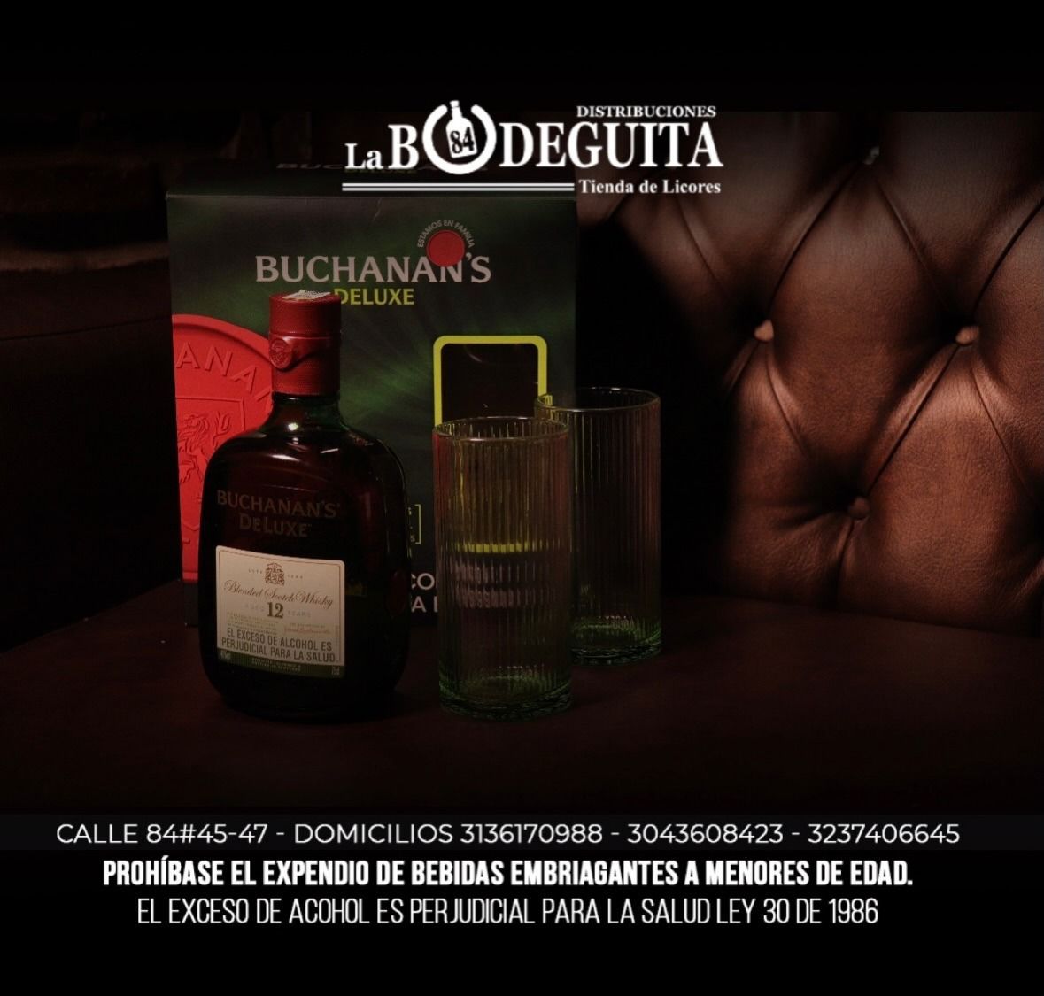 Botella de whisky Buchanan's y dos vasos con el logotipo de la tienda, sobre un fondo de cuero oscuro.
