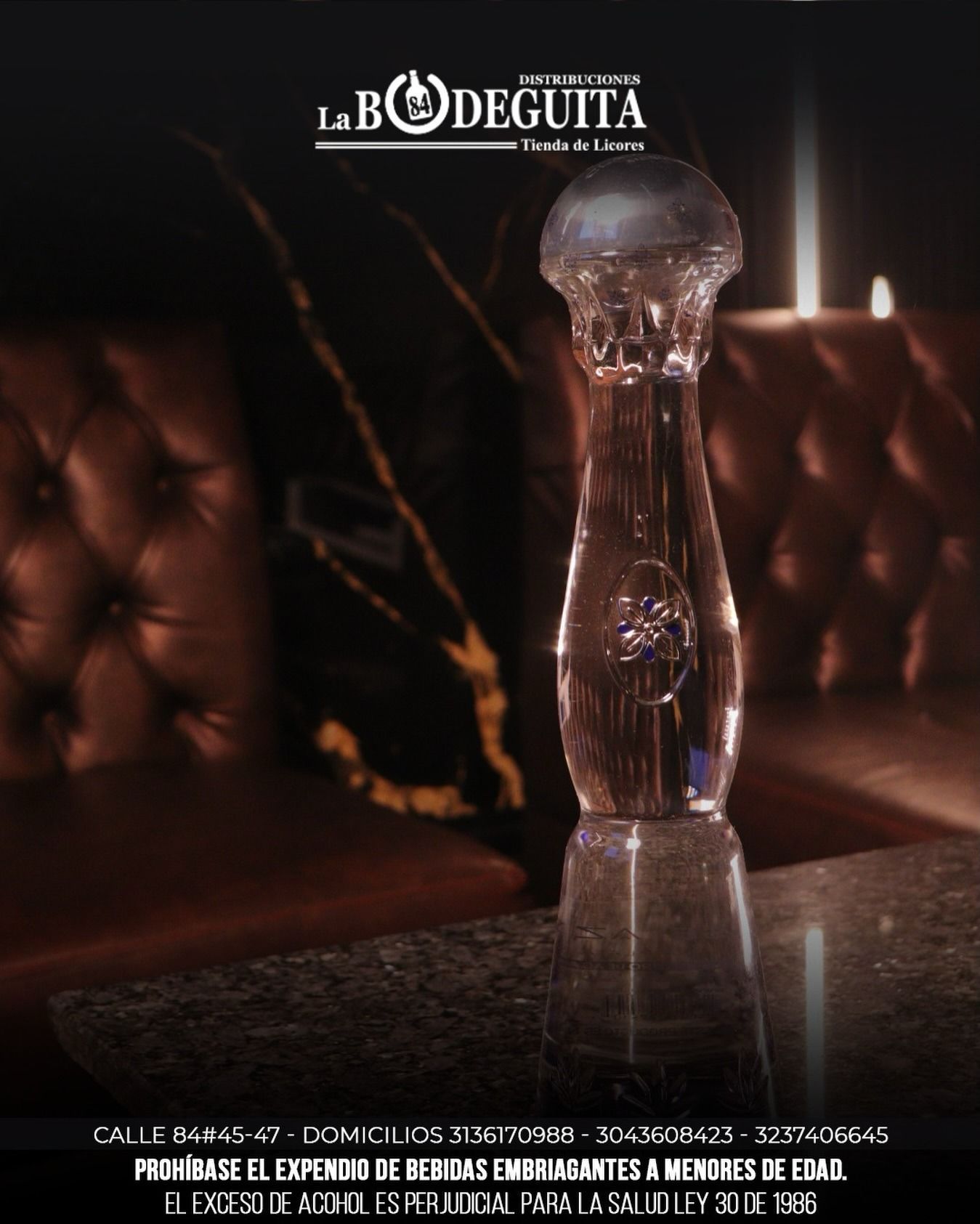 Botella de licor de vidrio sobre una mesa en un bar. El texto en la parte inferior advierte contra servir alcohol a menores.